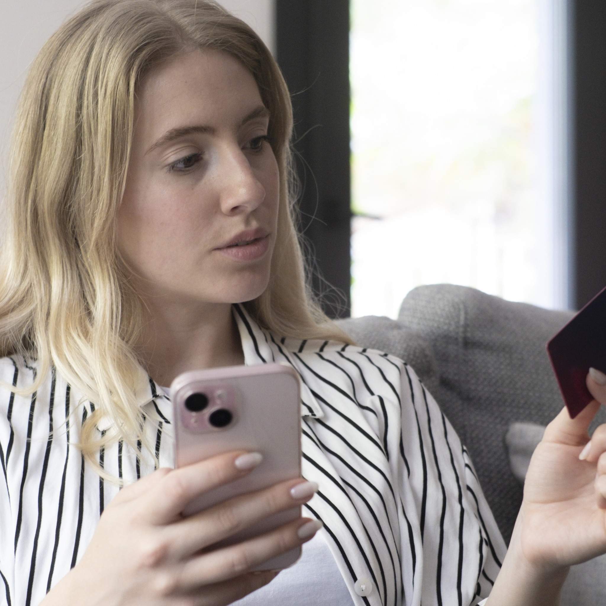 A woman comparing a credit card and her phone before applying for a starter card